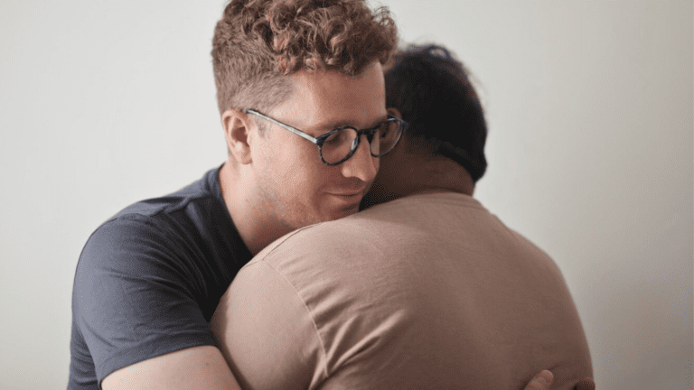 Two gay men embracing , portraying a moment of support for the impact of HIV Stigma on Gay Men's Health.