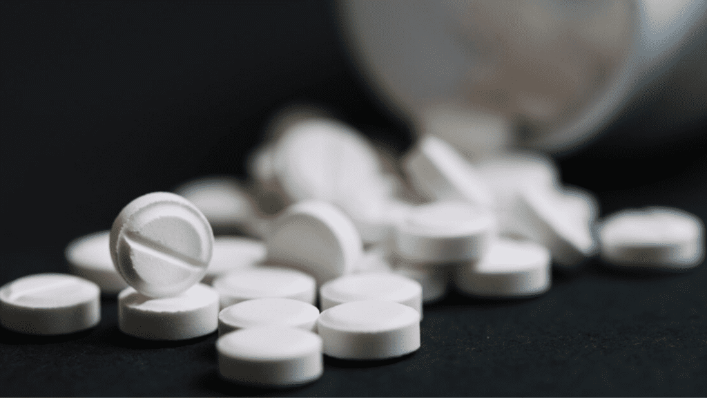 White prescription pills scattered on a surface, representing opioid medications.