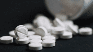 White prescription pills scattered on a surface, representing opioid medications.
