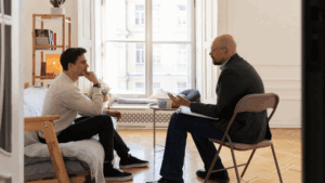 A gay man and a therapist during therapy, showing what typically takes place in a rehab for alcoholics.