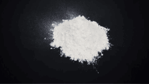 A close-up image of a white powder pile on a black surface, illustrating the drug cocaine or coke.