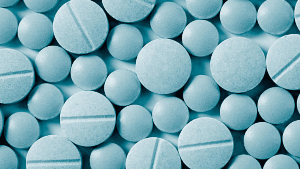 Blue tablets displayed on a background, exemplifying samples of the drug, roxicodone.