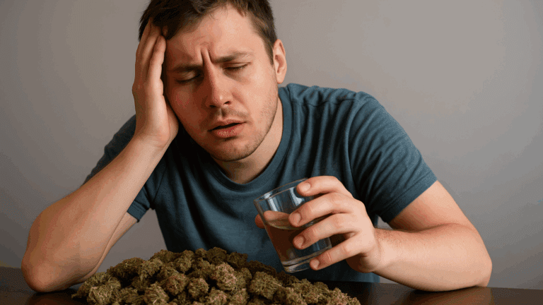 A gay man appears dizzy and disoriented while sitting, surrounded by a large amount of marijuana.