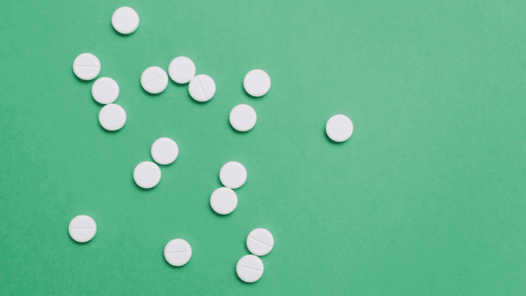 White round pills scattered on a green background, representing the drug, percocet.