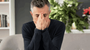 A gay heroin addict person looking depressed while sitting on a chair.