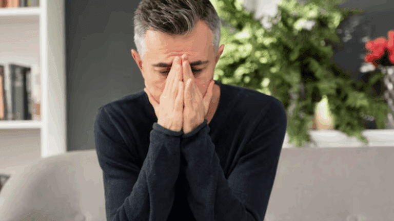 A gay heroin addict person looking depressed while sitting on a chair.