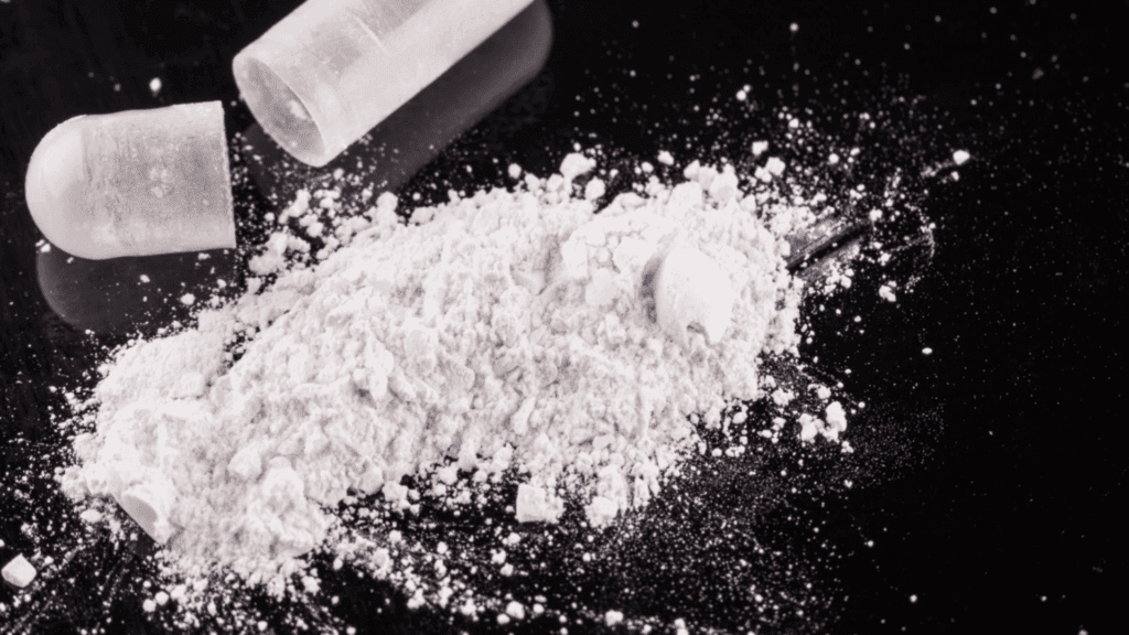 Powderized isotonitazene from a capsule on a black background.