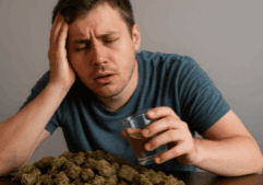 A gay man appears dizzy and disoriented while sitting, surrounded by a large amount of marijuana.