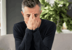A gay heroin addict person looking depressed while sitting on a chair.