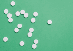 White round pills scattered on a green background, representing the drug, percocet.