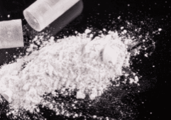 Powderized isotonitazene from a capsule on a black background.